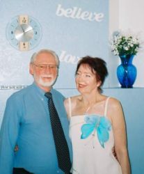 A woman lovingly looks at her husband, who holds her band and smiles