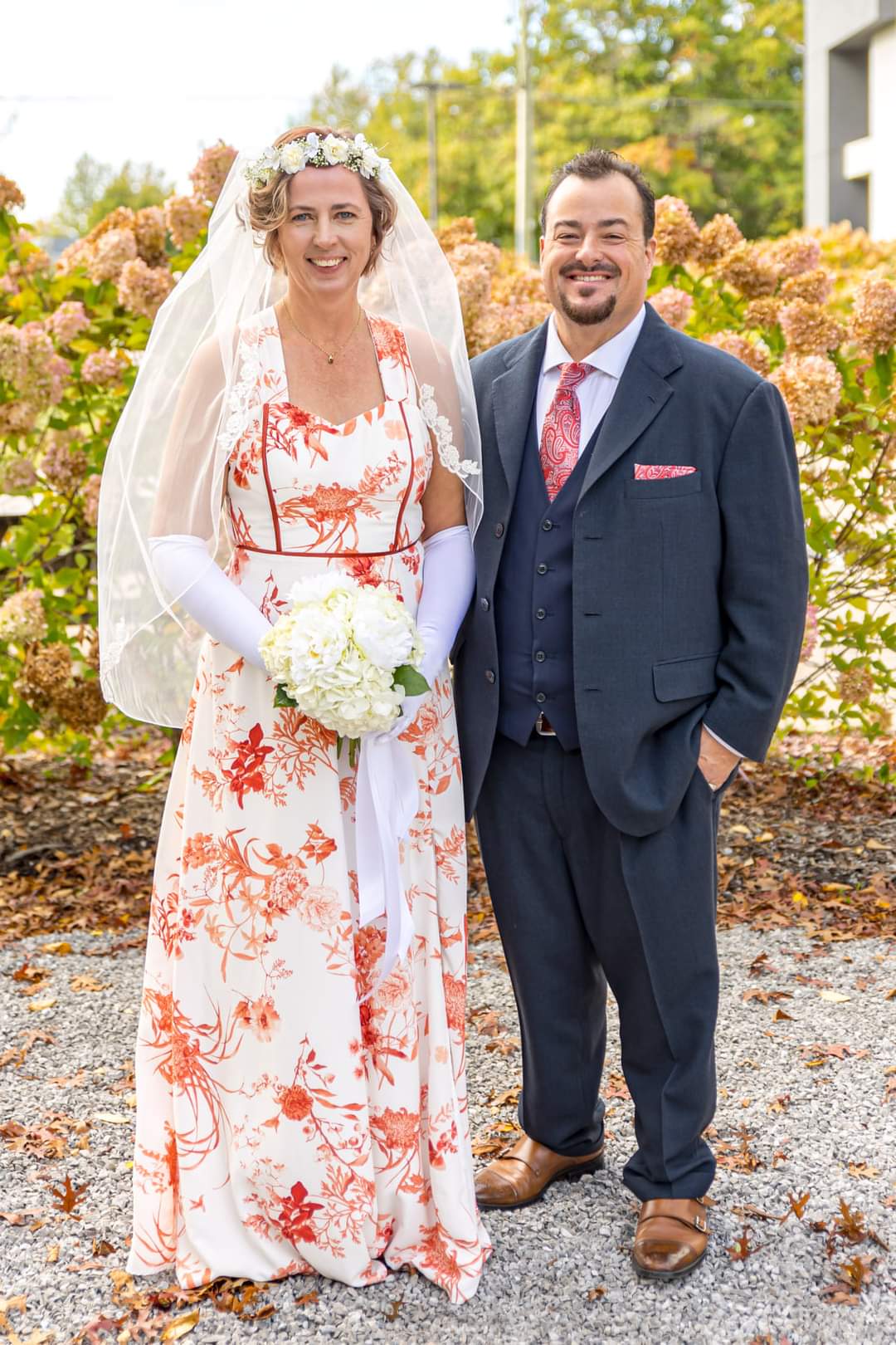 Very happy Christian couple pose proudly on their wedding day in front of autumn colours