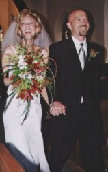 New Christian bride laughs while holding her flowers and her new husband's hand