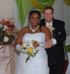 A man hold tightly on to his new bride as she stands in front of lovely flowers