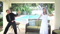 A man holds a fishing rod near a pool and pretends to hook his new bride