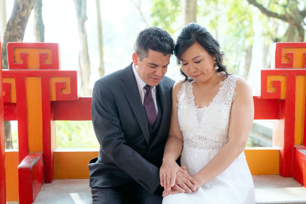 A newly married American man sits next to his new Chinese bride, at a park in Taiwan