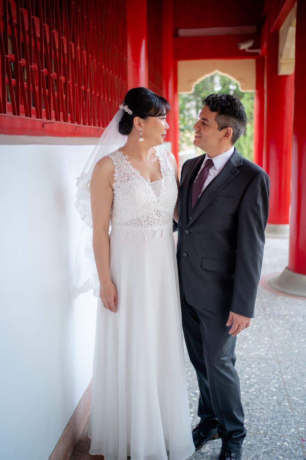 A newly married Christian couple gaze into each other's eyes next to pillars in Taiwan
