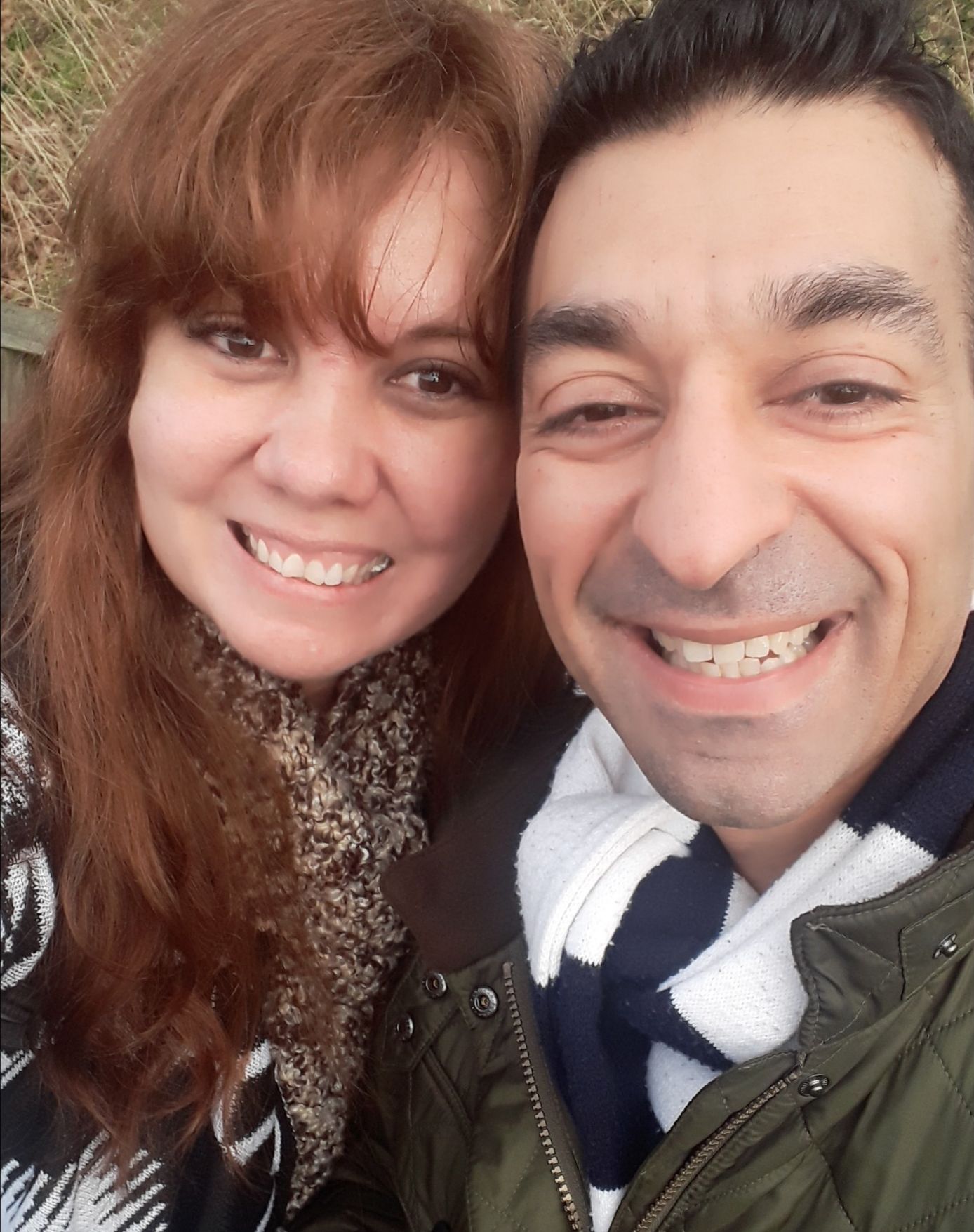 A couple pose outdoors in December while smiling for a selfie
