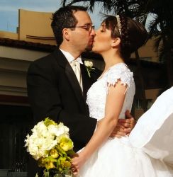 Beautiful Christian bride kisses her sweetheart while holding bridal bouquet