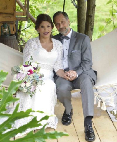Just married couple resting hand in hand in a hammock